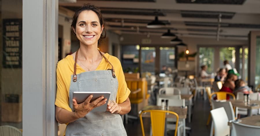 Mujer emprendedora sonriendo en su negocio, programa Emprende y Ahorra